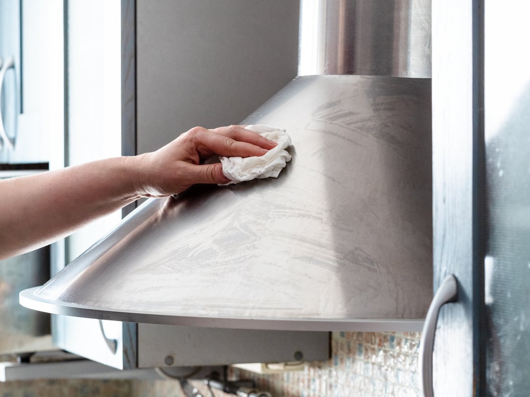 Female Hand Cleans Stainless Steel Kitchen Hood