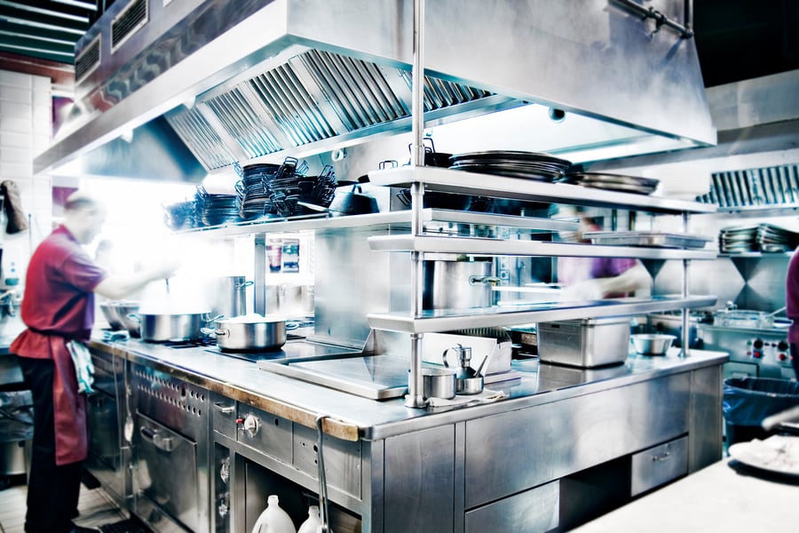 Man Stirring Pot in Stainless Steel Restaurant Kitchen